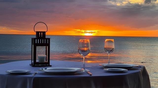Romantic waterfront dinner at sunset with candlelit table for two.