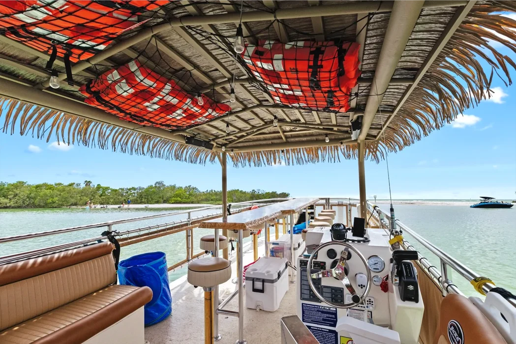 Tropical pontoon boat with thatched roof seating.