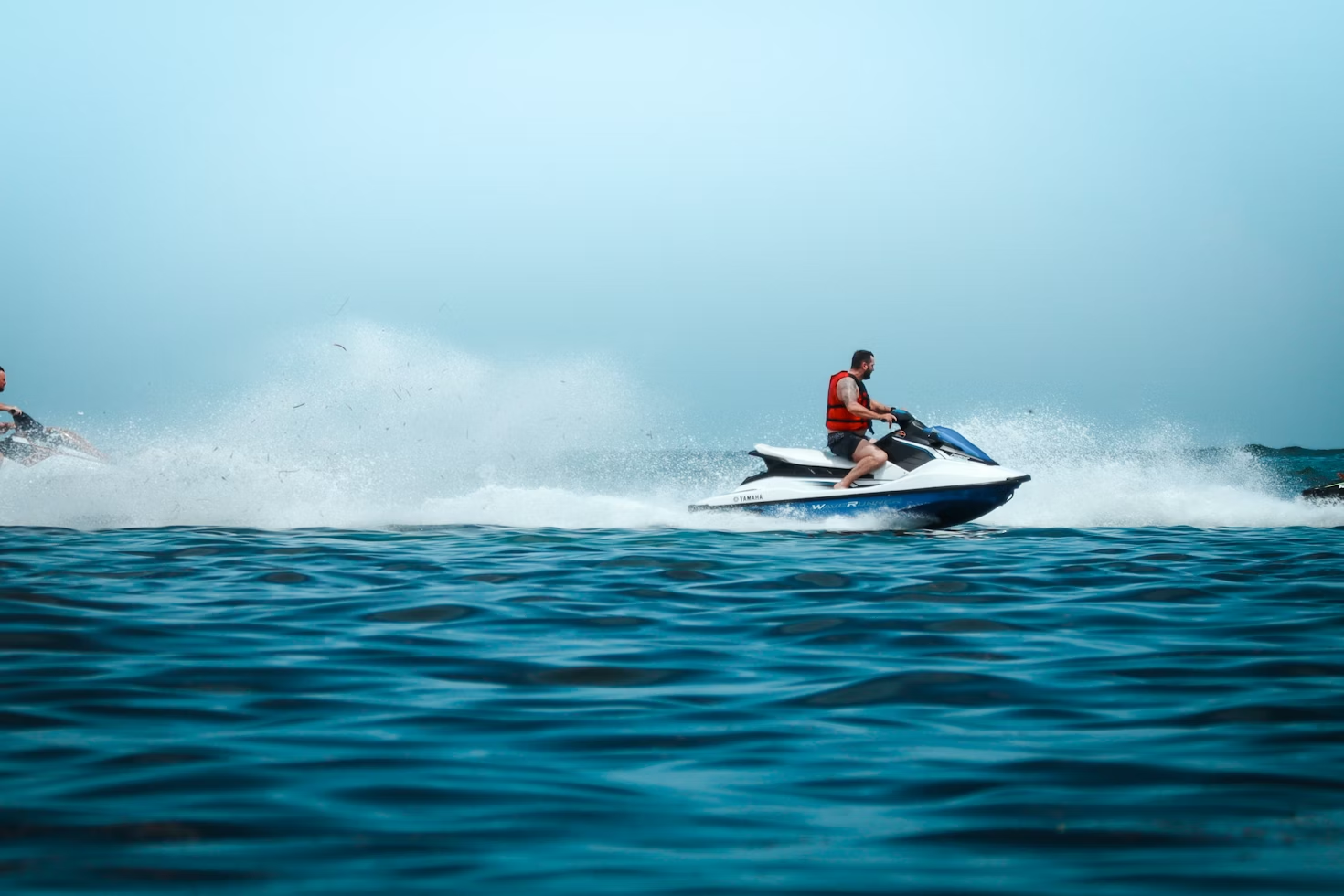 Jet ski rider speeding across water with spray trail.