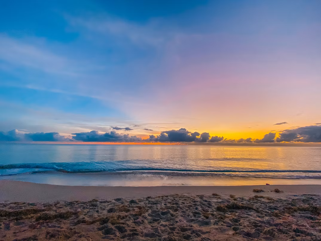 West Palm Beach sunset with waves and colorful horizon sky.