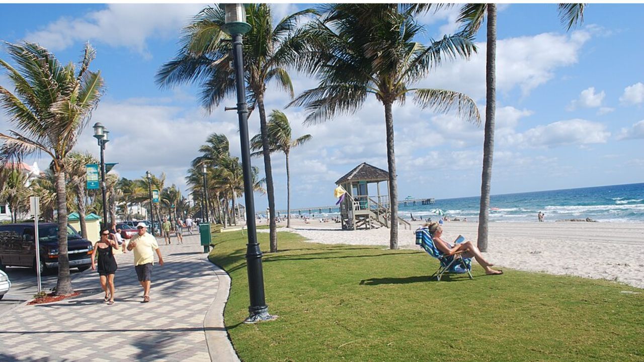 Deerfield Beach with palm trees, promenade, and shoreline. 