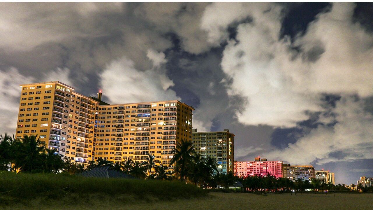 Pompano Beach skyline glowing over the sandy coast at night. 